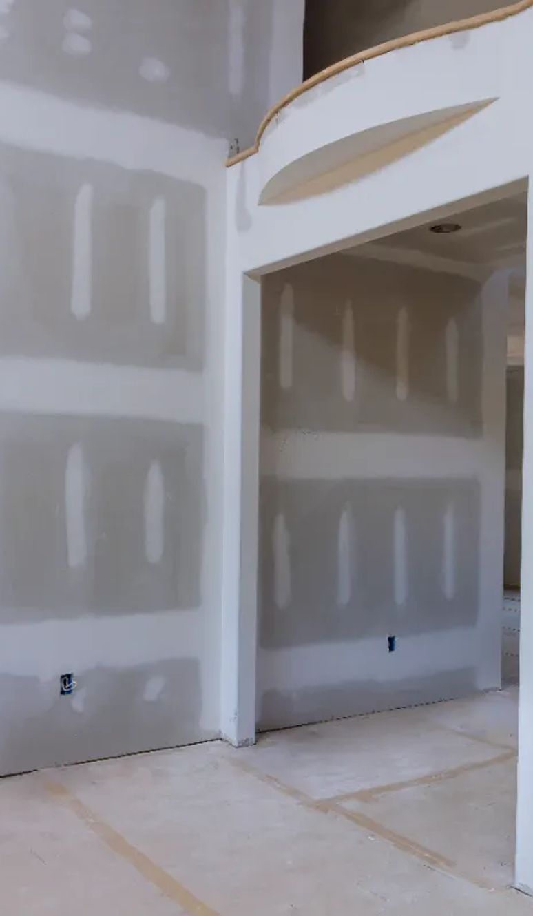Newly hung drywall in a room with a coffered ceiling, seams ready for paint