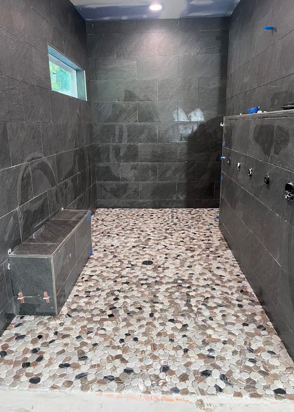 Dark slate tile shower with river-rock pebble floor and built-in bench
