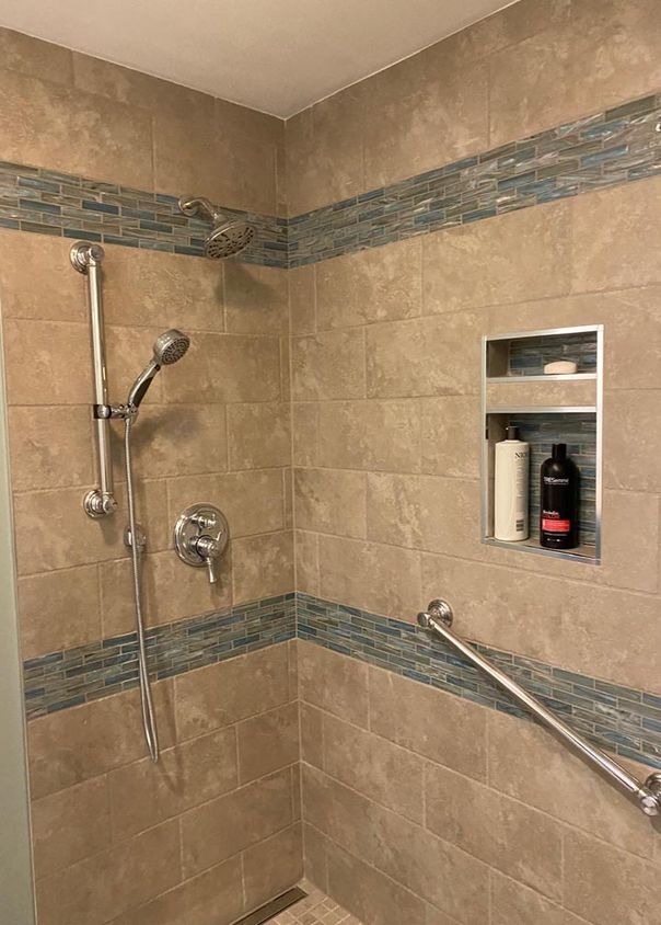 Tan tile shower with mosaic accent stripe and accessibility grab bars