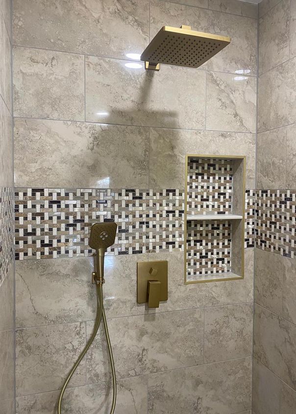 Travertine-look tile shower with mosaic accent band and brushed gold fixtures