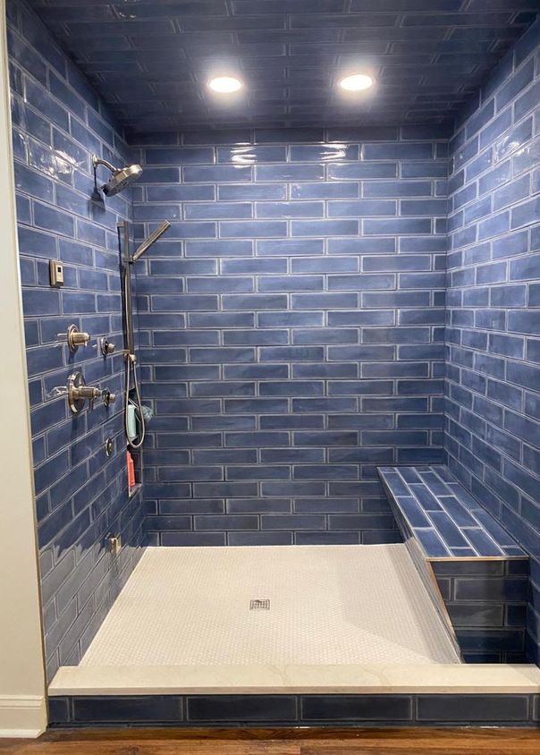 Bold blue subway tile shower with built-in bench and matte black fixtures