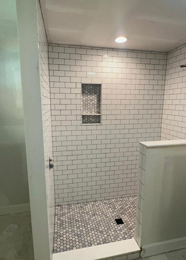 White subway tile shower with hexagonal mosaic floor and recessed niche