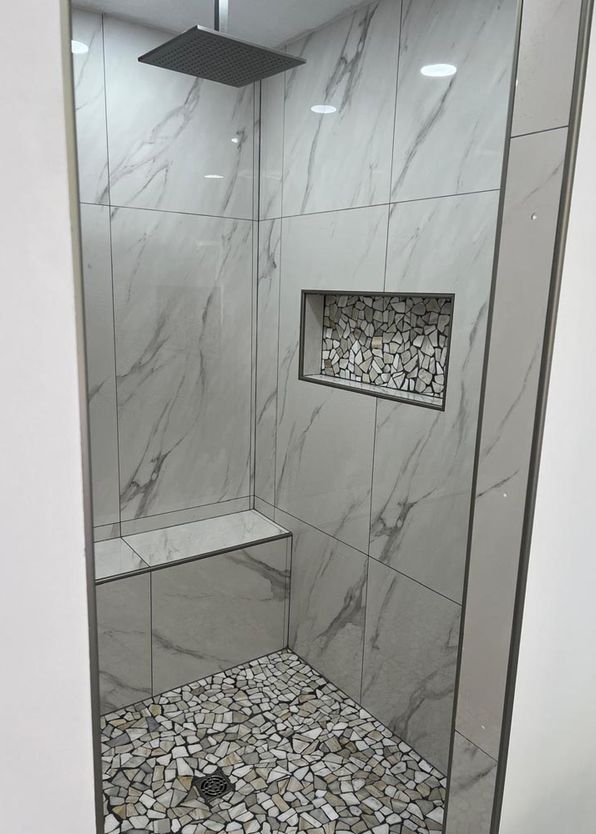 Marble-look tile walk-in shower with pebble mosaic floor and rainfall showerhead