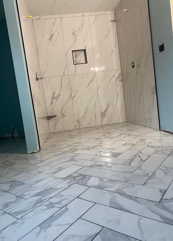 Marble-look tile bathroom with herringbone-pattern floor and walk-in shower
