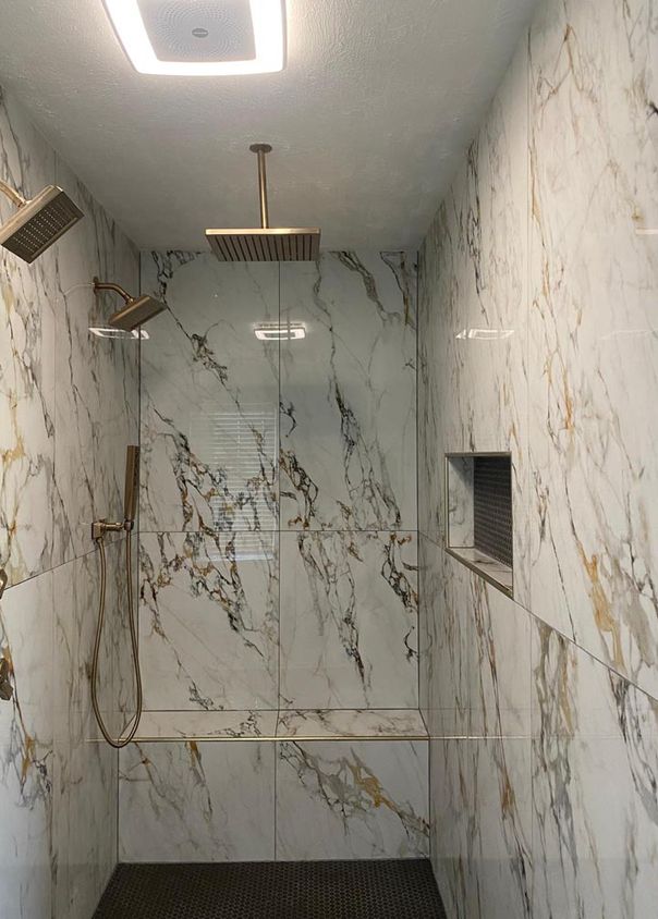 Calacatta-style marble shower with brass fixtures and dual rainfall showerheads