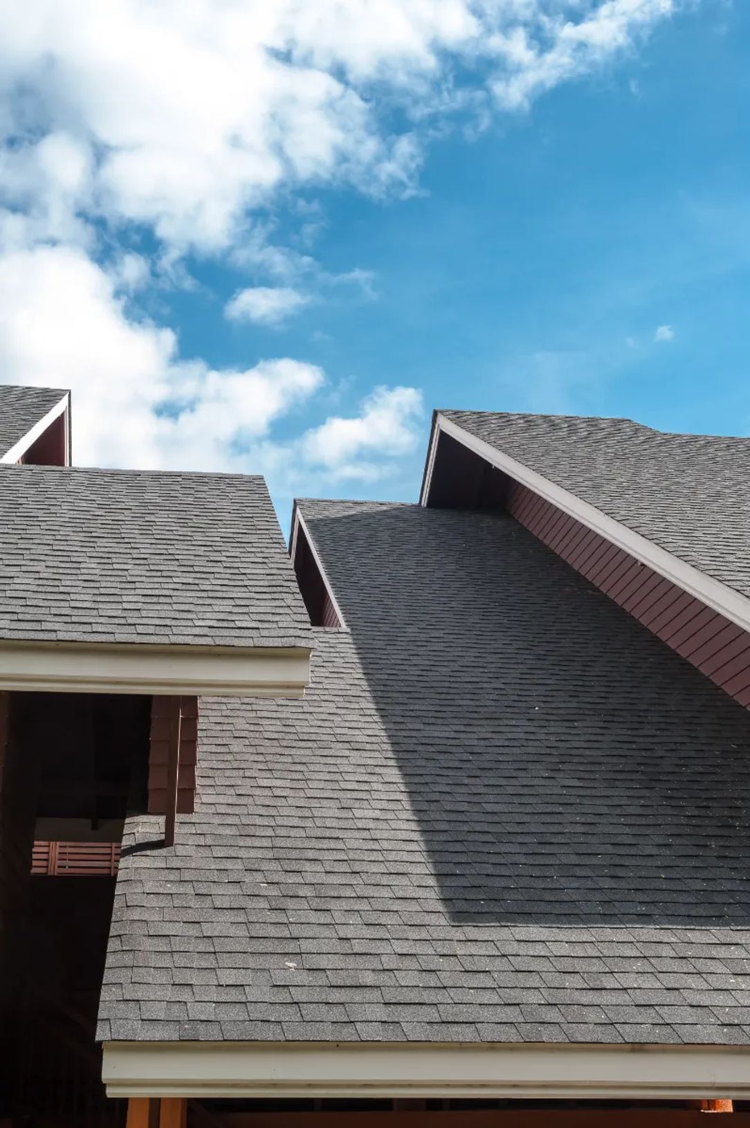 Close-up of gray asphalt shingle roof under blue sky